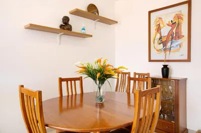 a dining room table with chairs and a vase of flowers at Cantinho Solpraia in Porto Santo