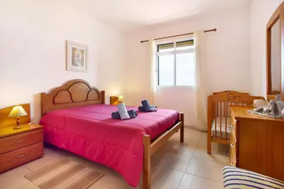 a bedroom with a large bed with a red blanket at Cantinho Solpraia in Porto Santo