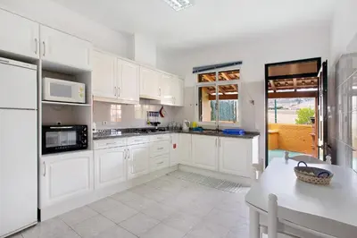 a white kitchen with white cabinets and a table at Cantinho Solpraia in Porto Santo