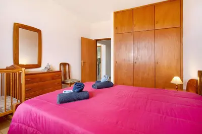 a bedroom with a pink bed with two blue towels at Cantinho Solpraia in Porto Santo