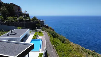 a house on a hill next to the ocean at Villa Blue Horizon by LovelyStay in Tábua