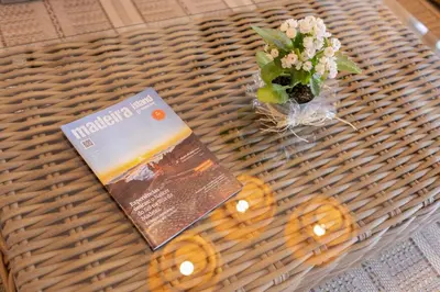 a book and a vase of flowers on a wicker table at Flag Hotel Madeira - Ribeira Brava in Ribeira Brava