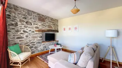 a living room with a couch and a stone wall at Bohome Nest by LovelyStay in Arco da Calheta