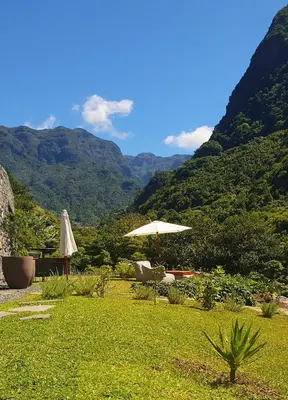 a patio with an umbrella and chairs with mountains in the background at Terrabona Nature & Vineyards in Boaventura