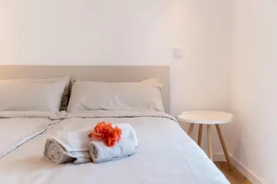 a white bed with towels on it with a table at GuestReady - A delightful stay in Porto Santo in Pontinhas