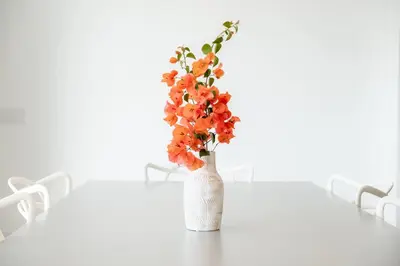 a white vase with orange flowers sitting on a table at GuestReady - A delightful stay in Porto Santo in Pontinhas