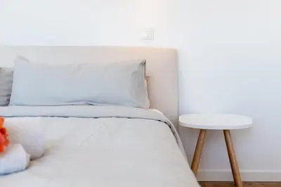 a bed with white sheets and a white table at GuestReady - A delightful stay in Porto Santo in Pontinhas
