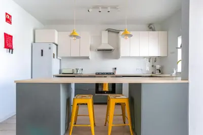 a kitchen with two yellow stools at a counter at Clifftop Nest Arrifana by Lisbeyond in Aljezur