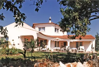 a white house with tables and chairs in front of it at Villa Lagos Algarve for families & friends, 6 bedrooms, 7 bathrooms, pool, BBQ, central heating in Pedra Alçada