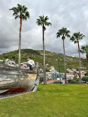 a man sitting on a boat in a park with palm trees at Blue Paradise Apartment in Ribeira Brava