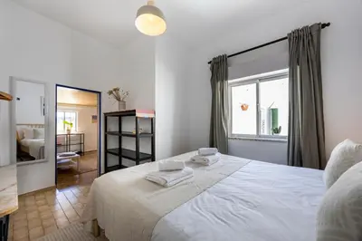 a bedroom with a large white bed and a window at Casa Ana Mar in Vila do Bispo