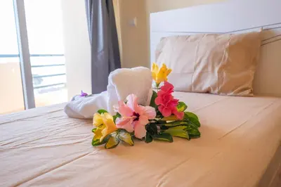 a bouquet of flowers sitting on top of a bed at Gracy Apartment at Garajau in Caniço