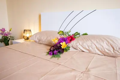 a bouquet of flowers sitting on top of a bed at Gracy Apartment at Garajau in Caniço