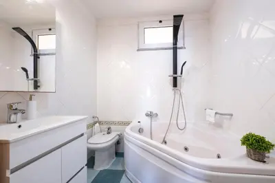 a white bathroom with a tub and a toilet at Gracy Apartment at Garajau in Caniço