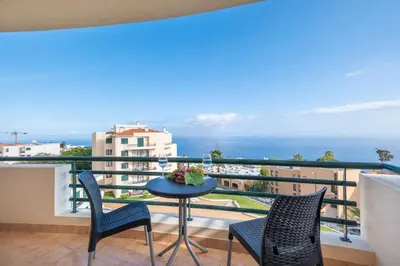 a balcony with a table and chairs and the ocean at Gracy Apartment at Garajau in Caniço