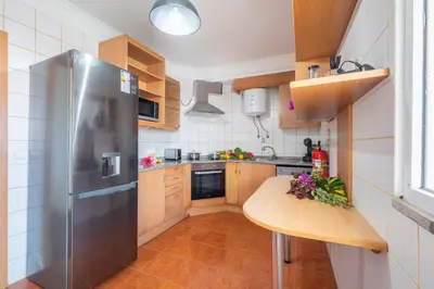 a kitchen with a stainless steel refrigerator and a wooden table at Gracy Apartment at Garajau in Caniço