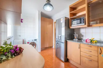 a kitchen with a table and a stainless steel refrigerator at Gracy Apartment at Garajau in Caniço