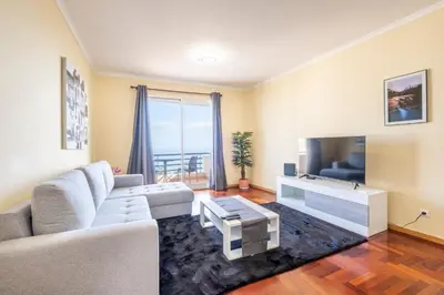 a living room with a couch and a tv at Gracy Apartment at Garajau in Caniço