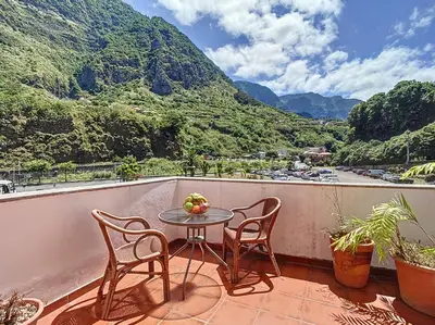 a table and chairs on a balcony with a view of a mountain at Amarelo Apartment by Atlantic Holiday in São Vicente