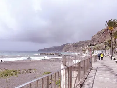 a boardwalk on a beach with people walking on it at Angela`s Loft in Ribeira Brava