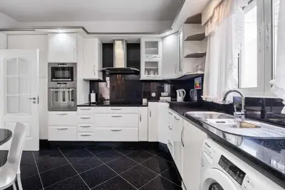 a kitchen with white cabinets and a black floor at Villa Funchal bay view in Funchal