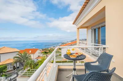 a balcony with a table and chairs and a view of the ocean at Villa Funchal bay view in Funchal