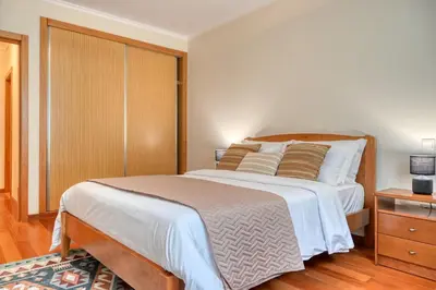 a bedroom with a large bed and a wooden cabinet at Baia Machico, a Home in Madeira in Machico
