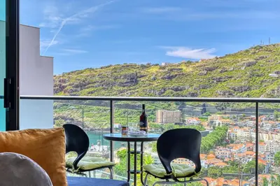 a room with a table and chairs and a mountain at Baia Machico, a Home in Madeira in Machico