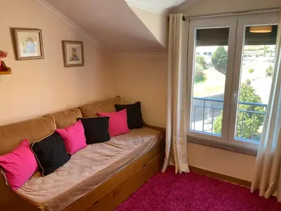 a couch with pink and black pillows in a room with a window at Moniz Apartment in Caniço