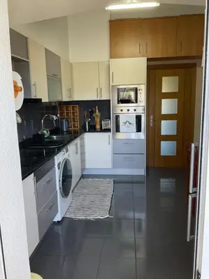 a kitchen with white appliances and wooden cabinets at Moniz Apartment in Caniço