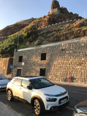 a white car parked in front of a stone building at Apartamentos do Mar Funchal in Funchal