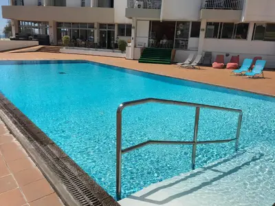 a large blue swimming pool with a rail in a building at Apartamentos do Mar Funchal in Funchal