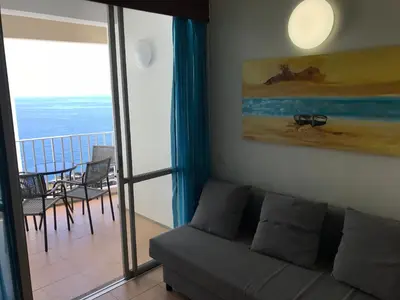 a living room with a couch and a balcony at Apartamentos do Mar Funchal in Funchal