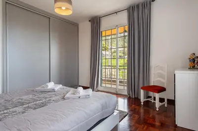 a bedroom with a bed and a window and a chair at Apartamento Maria in Canhas