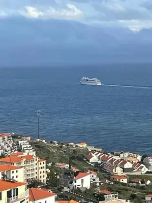 a cruise ship in the ocean next to a city at Por do Sol in Caniço