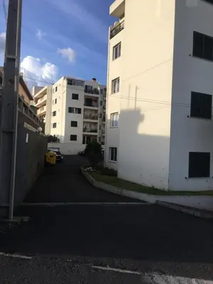 an empty parking lot next to two tall buildings at Por do Sol in Caniço