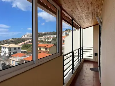 a balcony with windows and a view of a city at Por do Sol in Caniço