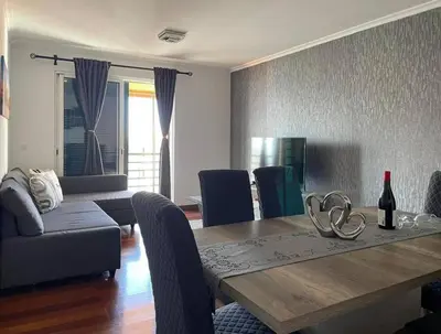 a living room with a dining table and a couch at Por do Sol in Caniço