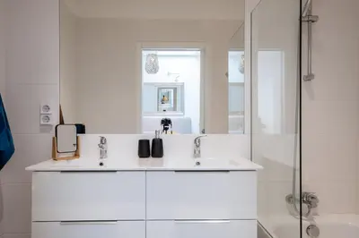 a white bathroom with two sinks and a shower at GuestReady - Anakaj House in Funchal