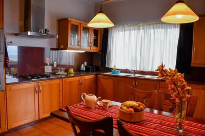 a kitchen with a table with a bowl of fruit on it at Bluehouse Paraiso á beira Mar in São Vicente