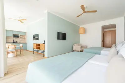 a bedroom with a large bed and a kitchen at Studios by Aqua Natura Hotels in Porto Moniz