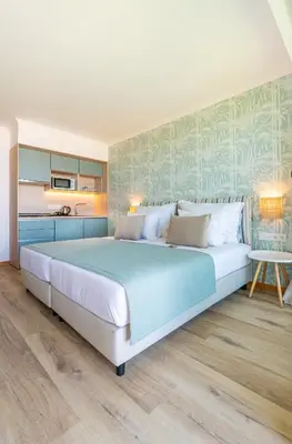 a bedroom with a large bed and a kitchen at Studios by Aqua Natura Hotels in Porto Moniz