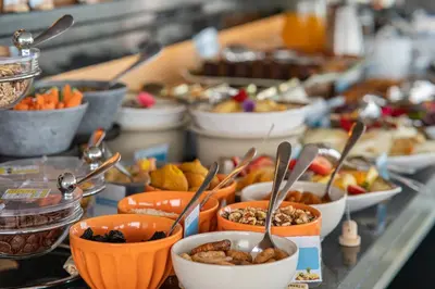 a buffet line with bowls of food and spoons at Studios by Aqua Natura Hotels in Porto Moniz