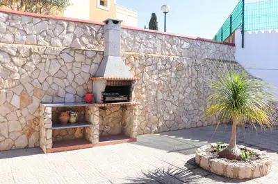 a stone wall with a pizza oven next to a tree at Luxury Villa with ocean view in Luz