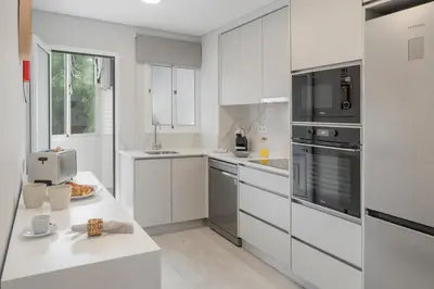 a white kitchen with white cabinets and appliances at Barreiros III by An Island Apart in Funchal