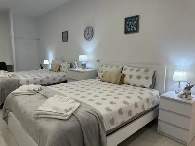 a bedroom with two beds and a clock on the wall at Funchal-Studio-Sleeps4-FreeParking in Funchal
