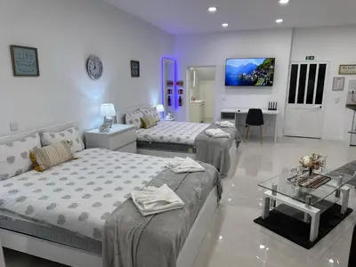 a bedroom with three beds and a table and a tv at Funchal-Studio-Sleeps4-FreeParking in Funchal