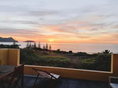 a view of a sunset from a balcony with chairs at The Beach House in Porto Santo