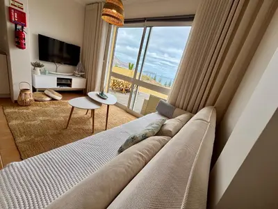 a living room with a couch and a large window at The Beach House in Porto Santo