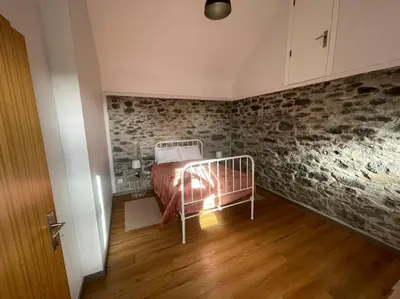 a bedroom with a bed and a stone wall at Casa Rustica da Maloeira in Fajã da Ovelha